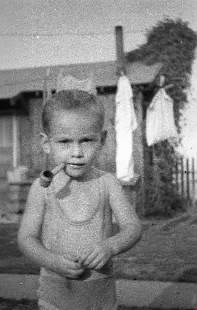 black and white photo of a kid with a pipe in his mouth