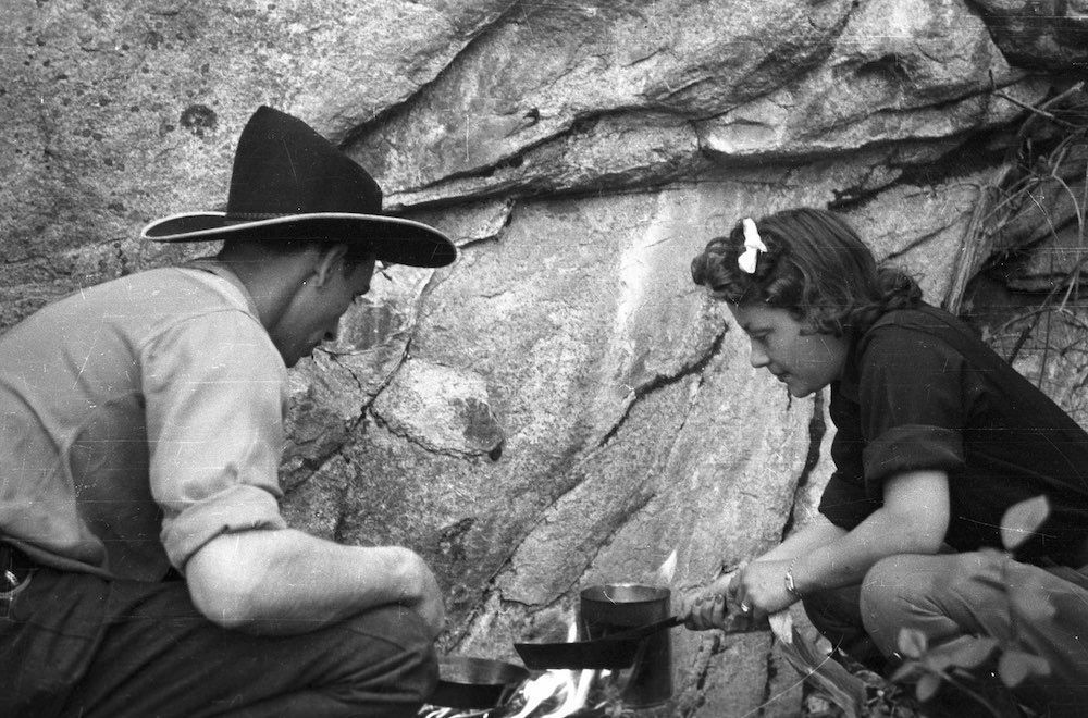 A man and a girl are cooking over a campfire