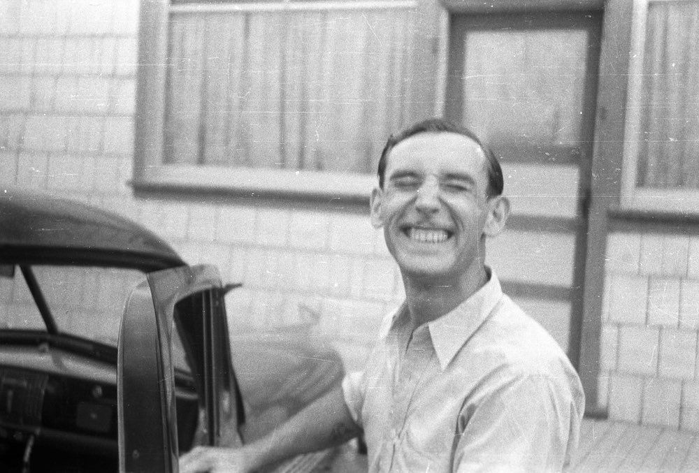A man is smiling while getting out of a car.