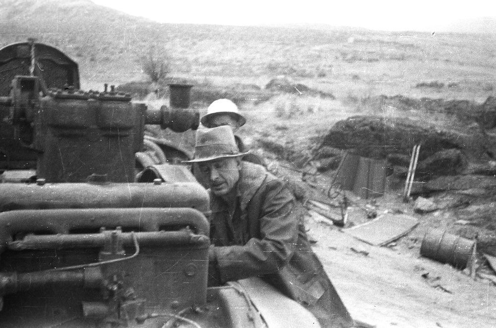 A man in a hat is sitting on top of a tank.