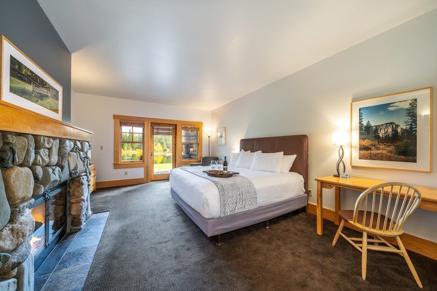 A bedroom with a king size bed , desk , chair and fireplace.