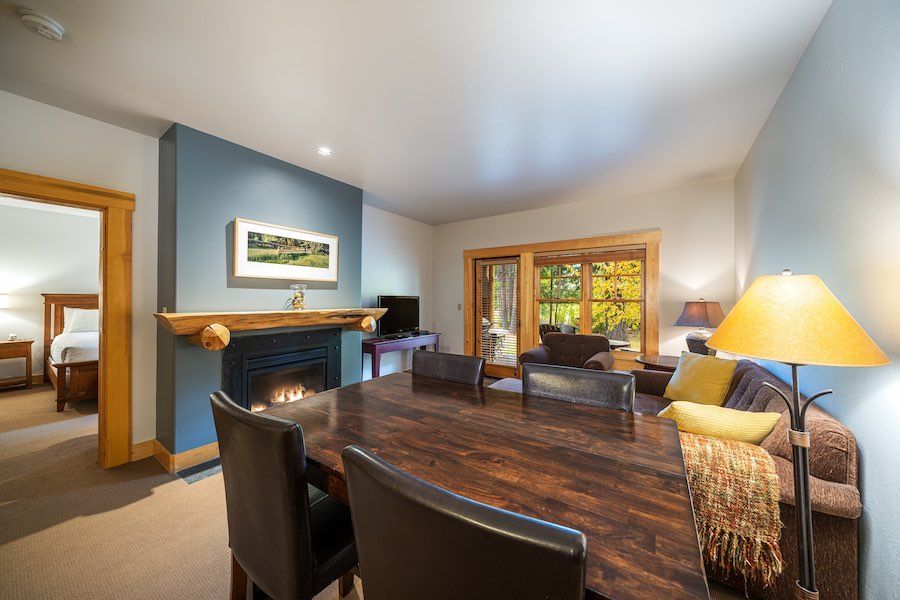 A living room with a wooden table and chairs and a fireplace.