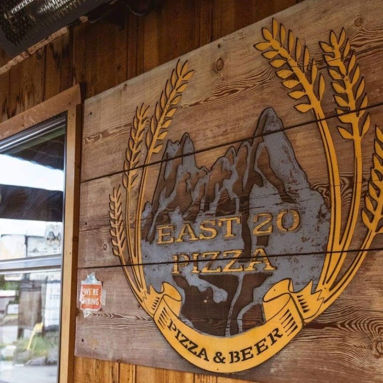 A wooden sign for east 20 pizza and beer