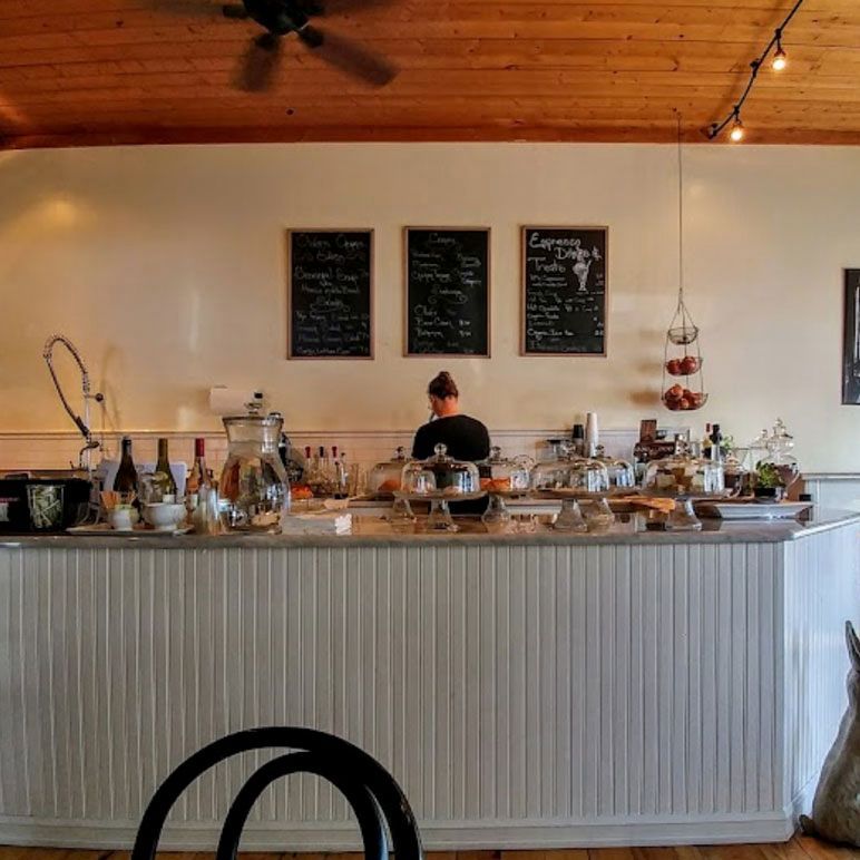 A woman stands behind a counter in a restaurant