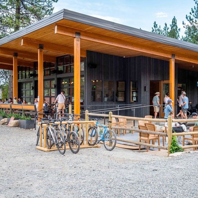 A group of people are standing outside of a building with bikes parked in front of it.