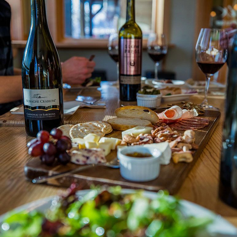 A bottle of wine sits on a table next to a plate of food