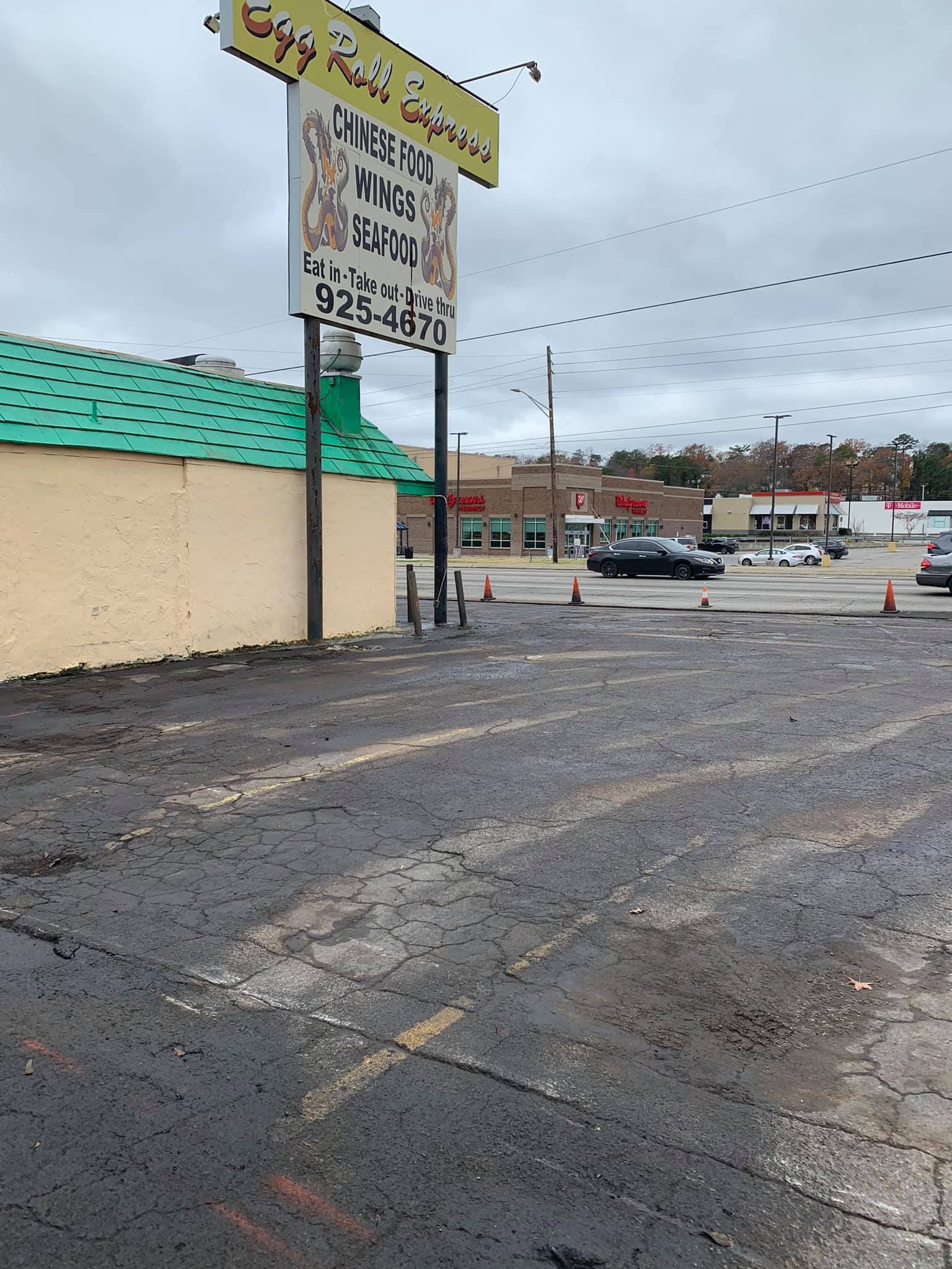A wide, deep crack runs diagonally across a newly paved asphalt parking lot with white painted lines.