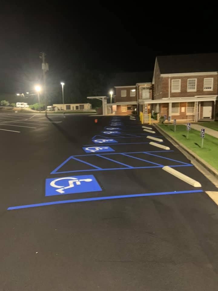A night view of a parking lot with several blue-painted accessible parking spaces marked with wheelchair symbols.