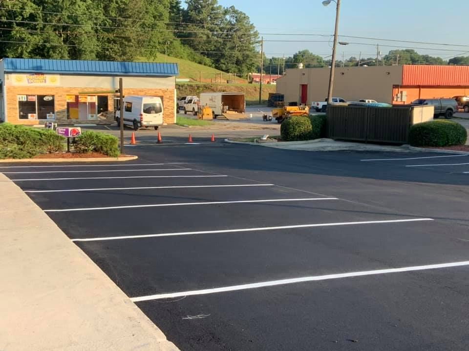 A newly paved parking lot with freshly painted white lines, adjacent to a single-story commercial building.