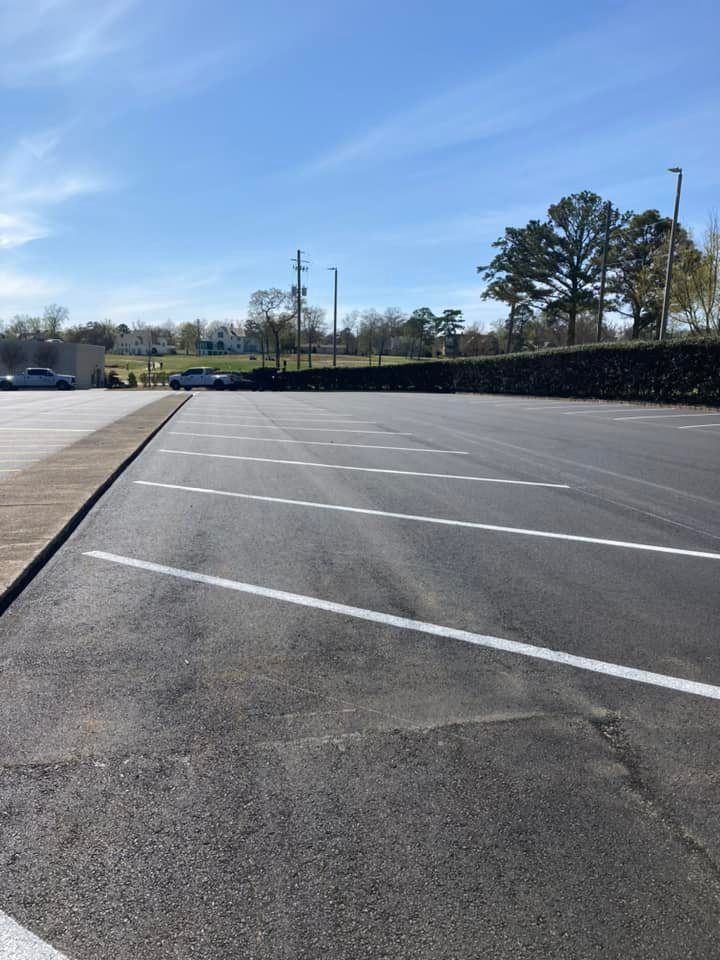 Empty asphalt parking lot with diagonal white painted lines on a clear, sunny day.