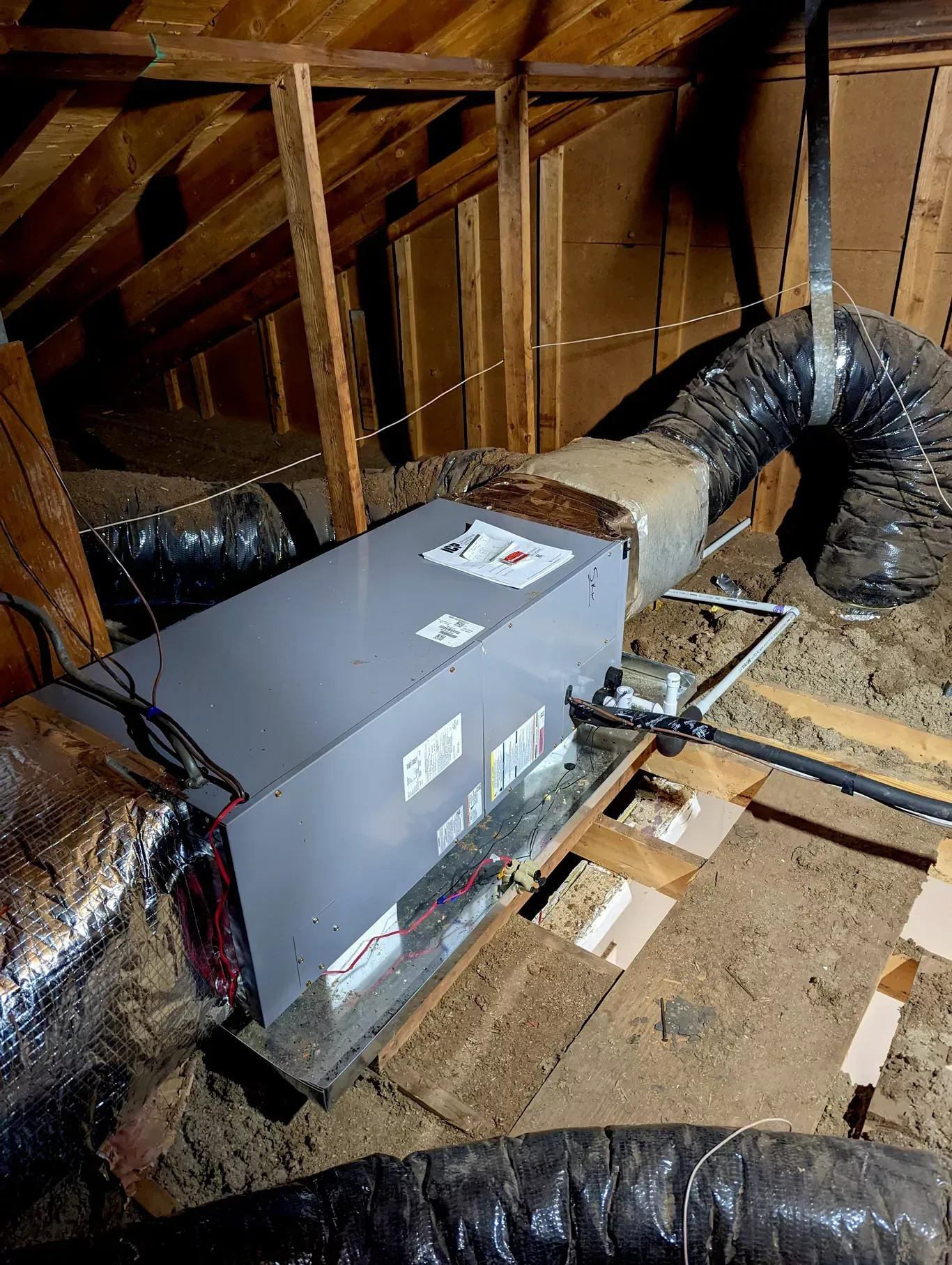 An air conditioner is sitting in the attic of a house.
