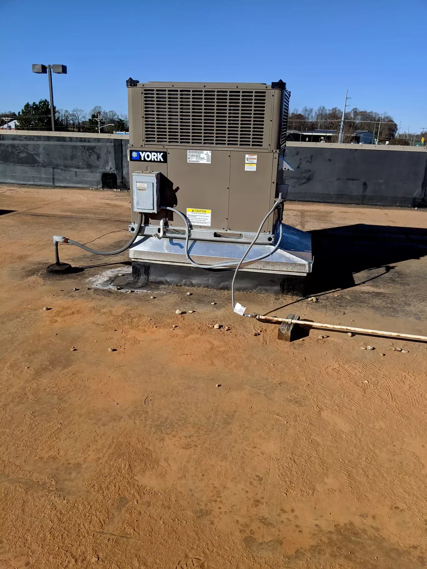 A large air conditioner is sitting on top of a dirt field.