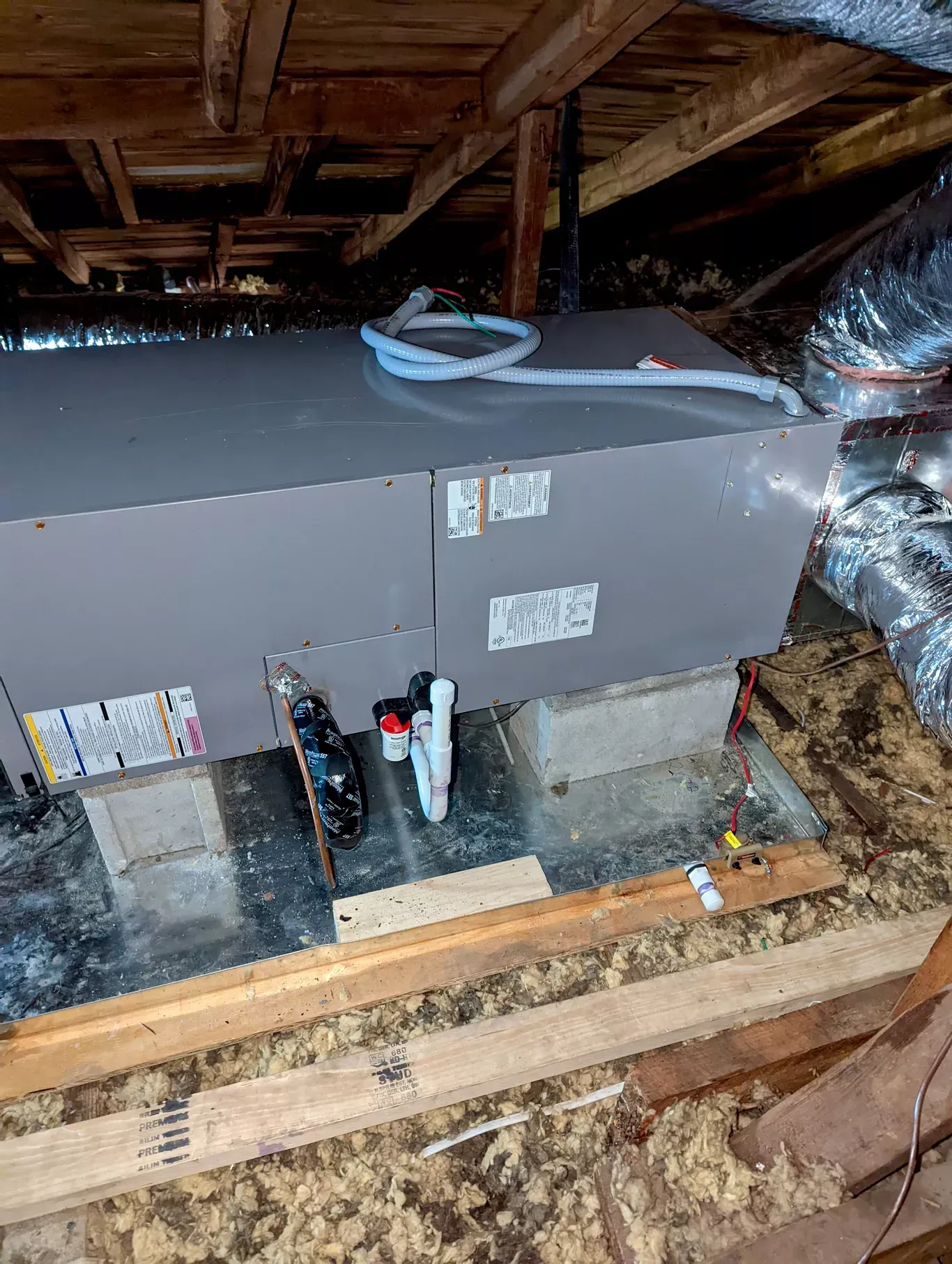 An air conditioner is sitting in the attic of a house.