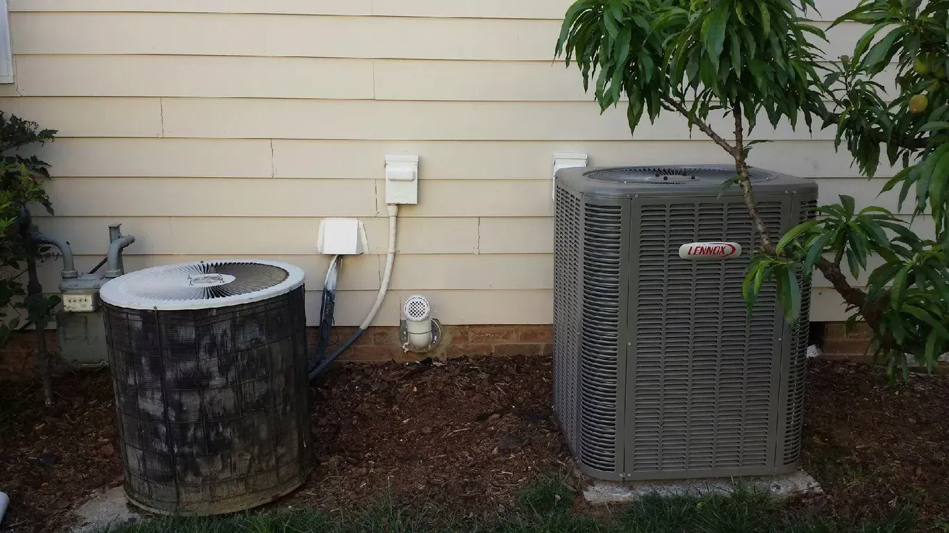 A couple of air conditioners are sitting next to each other on the side of a house.