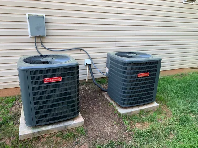 Two air conditioners are sitting next to each other on the side of a house.