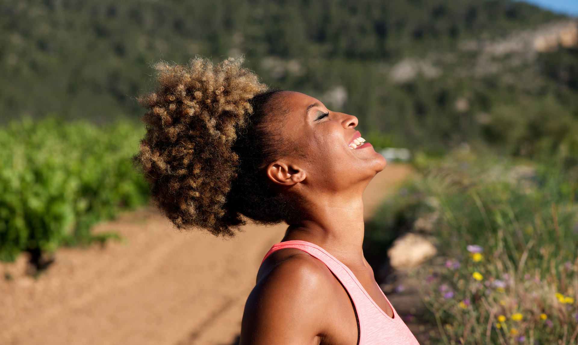 Woman with curly hair, smiling with her face tilted upward in outdoor setting. Woman with curly hair, smiling with her face tilted upward in outdoor setting.