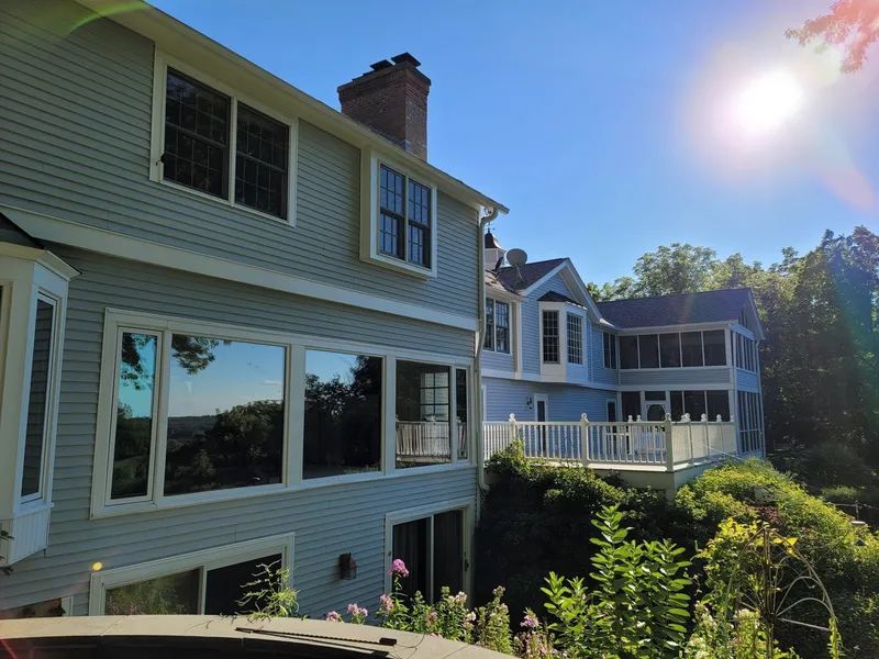 Two-story blue houses with large windows and deck against a bright sunny sky.