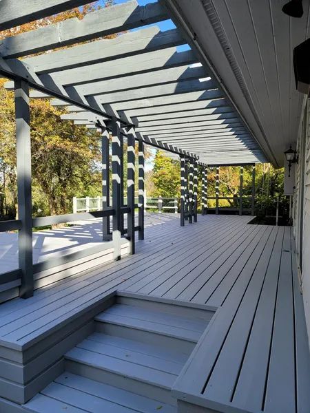 Gray-painted wooden deck with pergola; steps lead up to bench seating.