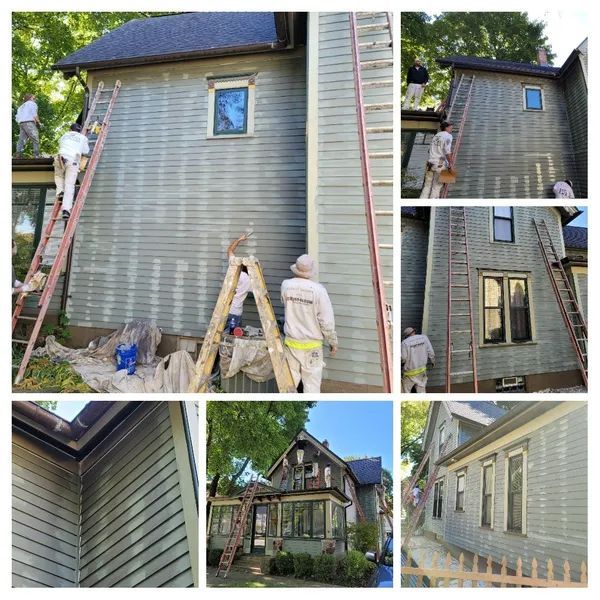House being painted by several people; ladders, siding, and green paint.