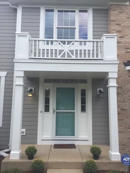 Gray house front entrance with white trim, porch, and door.