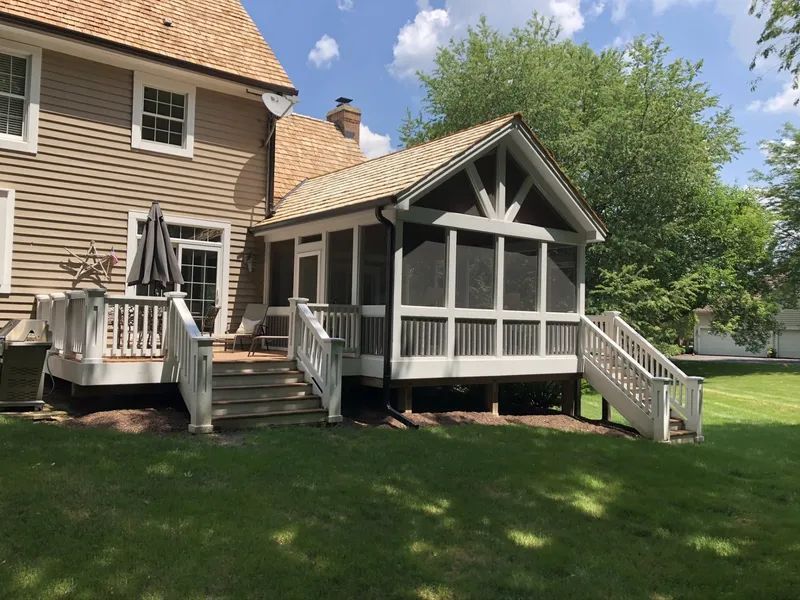 Screened porch with white trim, attached to a tan house with a deck; on green grass.