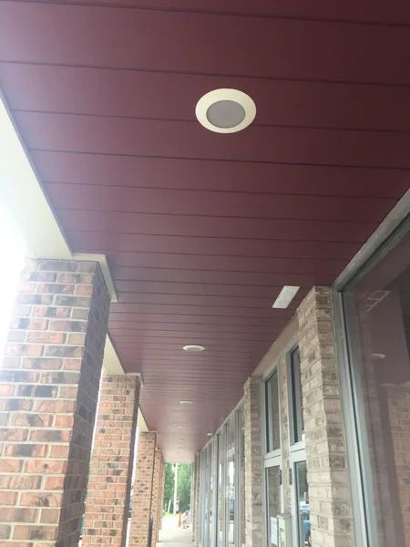 Red awning ceiling with inset lights; brick pillars and a row of windows on the right.