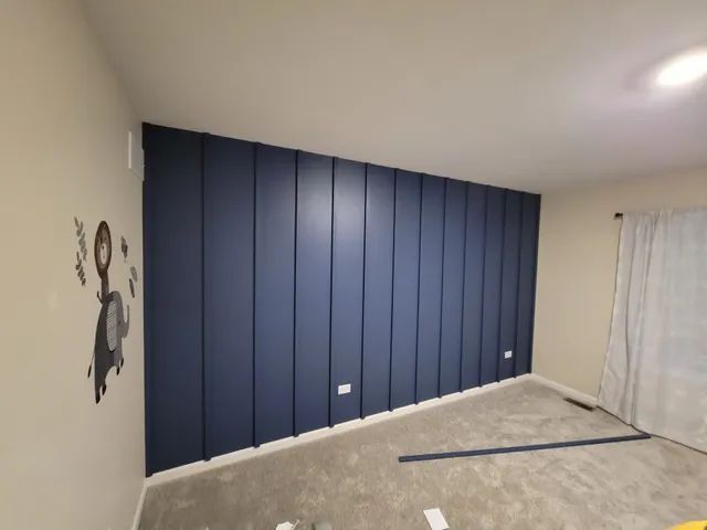 Navy blue vertical panel wall in a room with neutral walls and carpet.