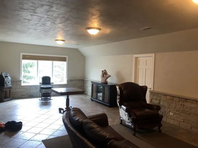 A finished basement with a brown leather sofa, recliner, and small table near a window.