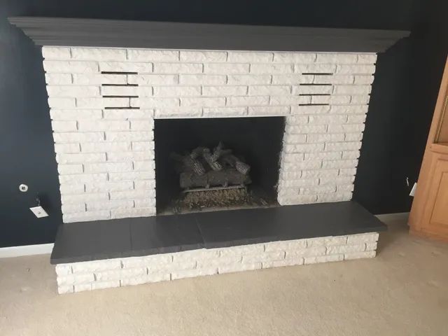 White brick fireplace with dark gray hearth and mantel; black interior.