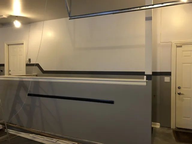 Garage interior with white and gray walls, a door, and a metal bar along the top.