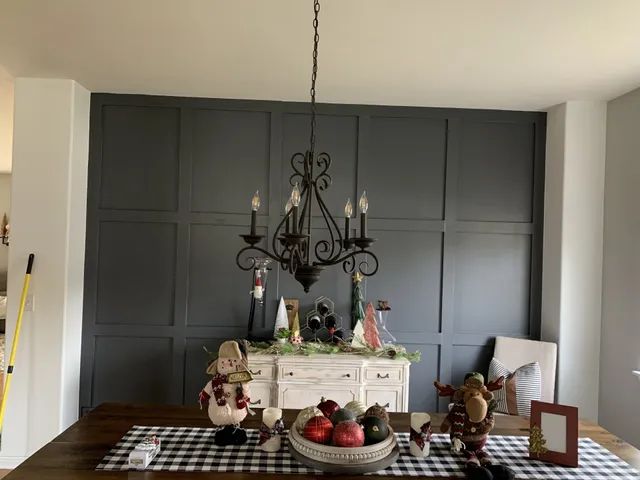 Dining room with dark gray accent wall, chandelier, buffet table, decorated for the holidays.