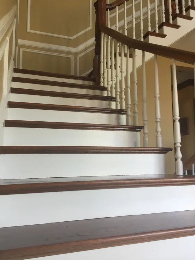 Wooden staircase with white risers and brown treads and handrail.