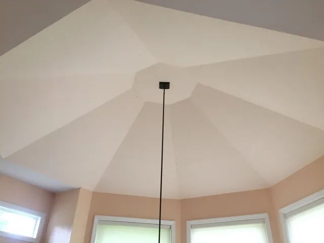 Off-white octagonal ceiling with a black light fixture. Light-colored walls, windows at the bottom.