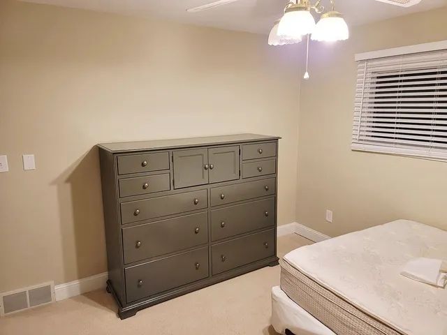 Bedroom with a large gray dresser, a bed with white sheets, and a window with blinds.