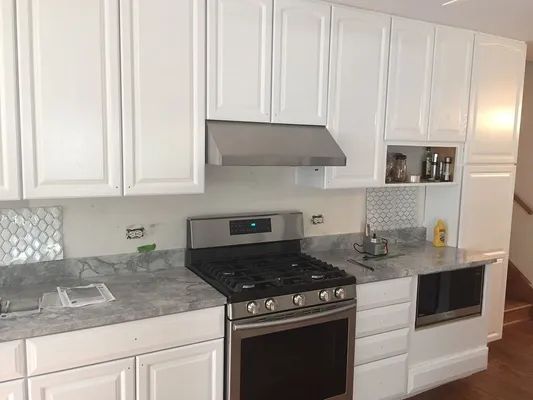 White kitchen with stainless steel appliances and gray countertops.