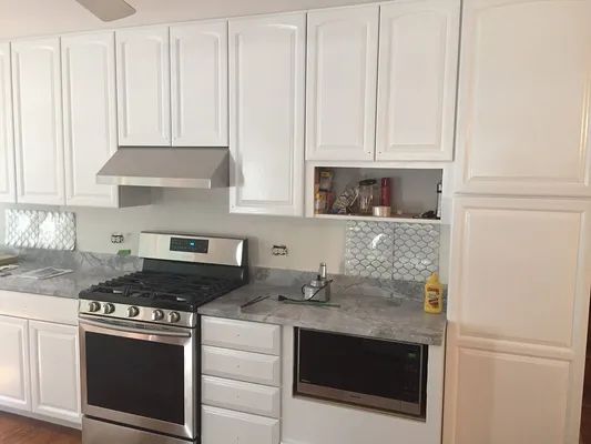 White kitchen cabinets with stainless steel appliances and granite countertops.