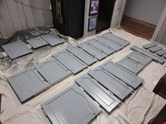 Gray painted cabinet doors drying on a drop cloth.