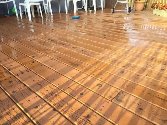 Wet, wooden deck with sunlight creating shadows.  Outdoor setting.