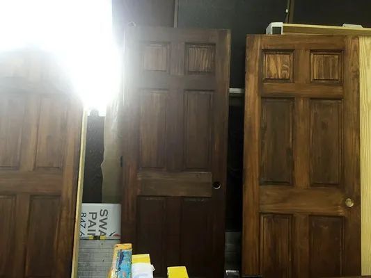 Three stained wooden doors in a workshop. The middle door is slightly open.