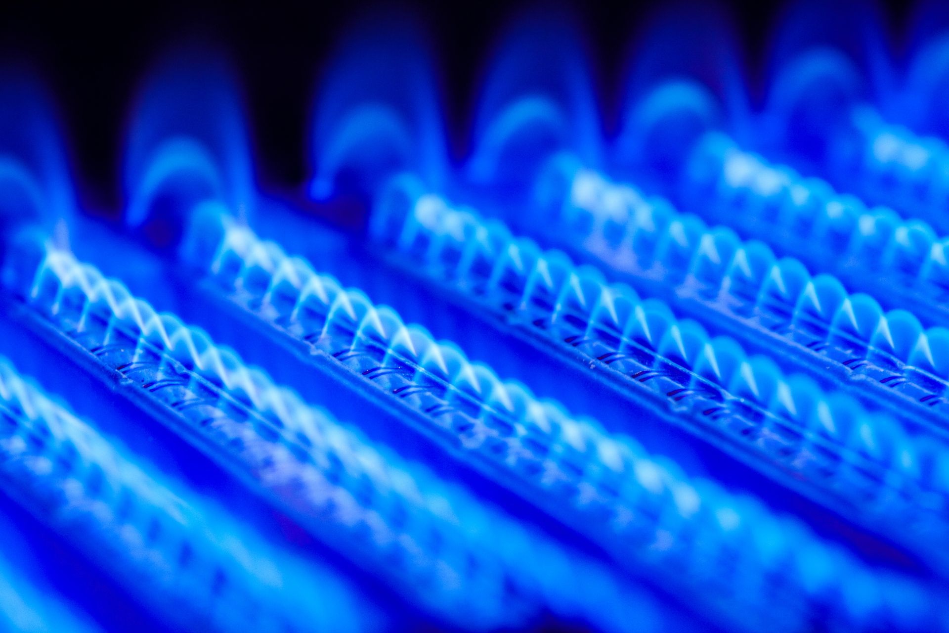 Un gros plan d'un brûleur à gaz avec des flammes bleues qui en sortent.