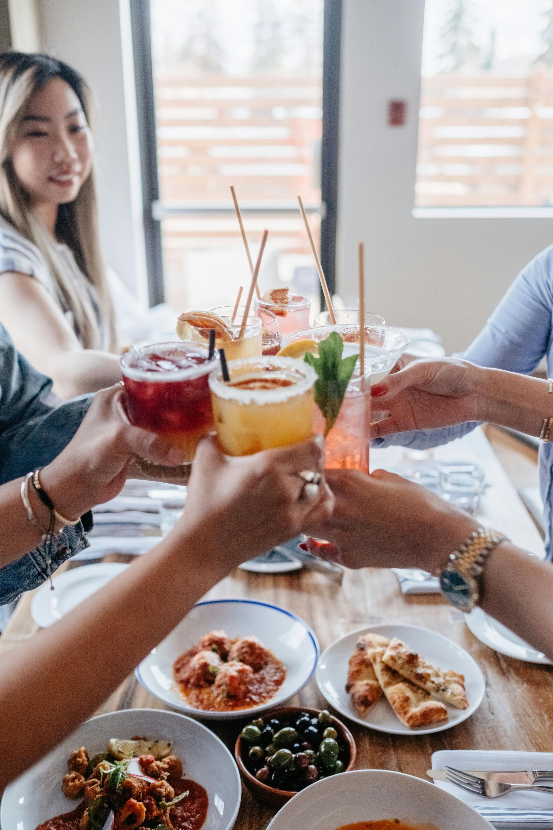 A group of people are sitting at a table toasting with drinks.