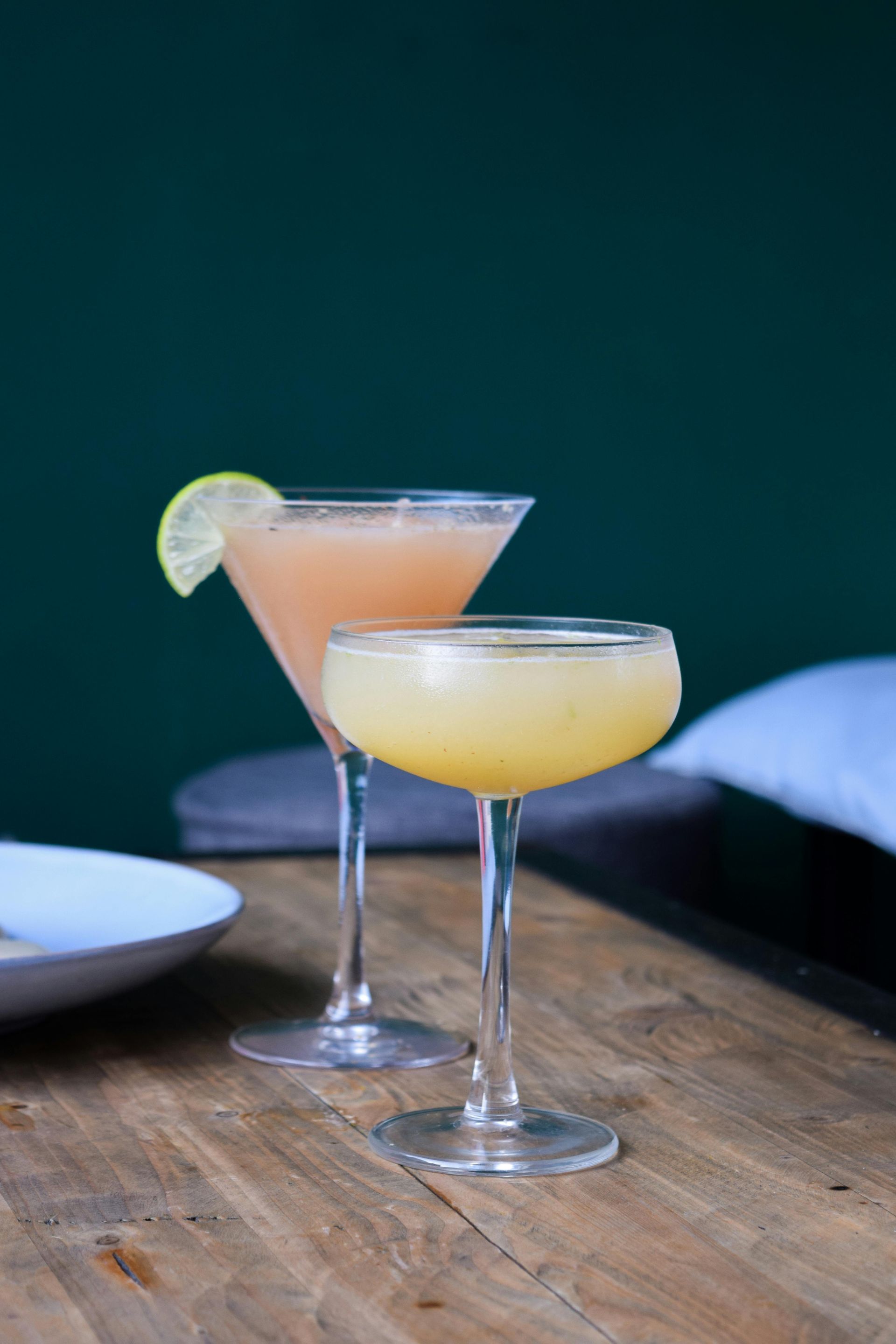 Two cocktails are sitting on a wooden table.