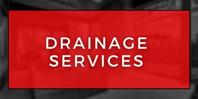 Red sign with white text reading “DRAINAGE SERVICES”