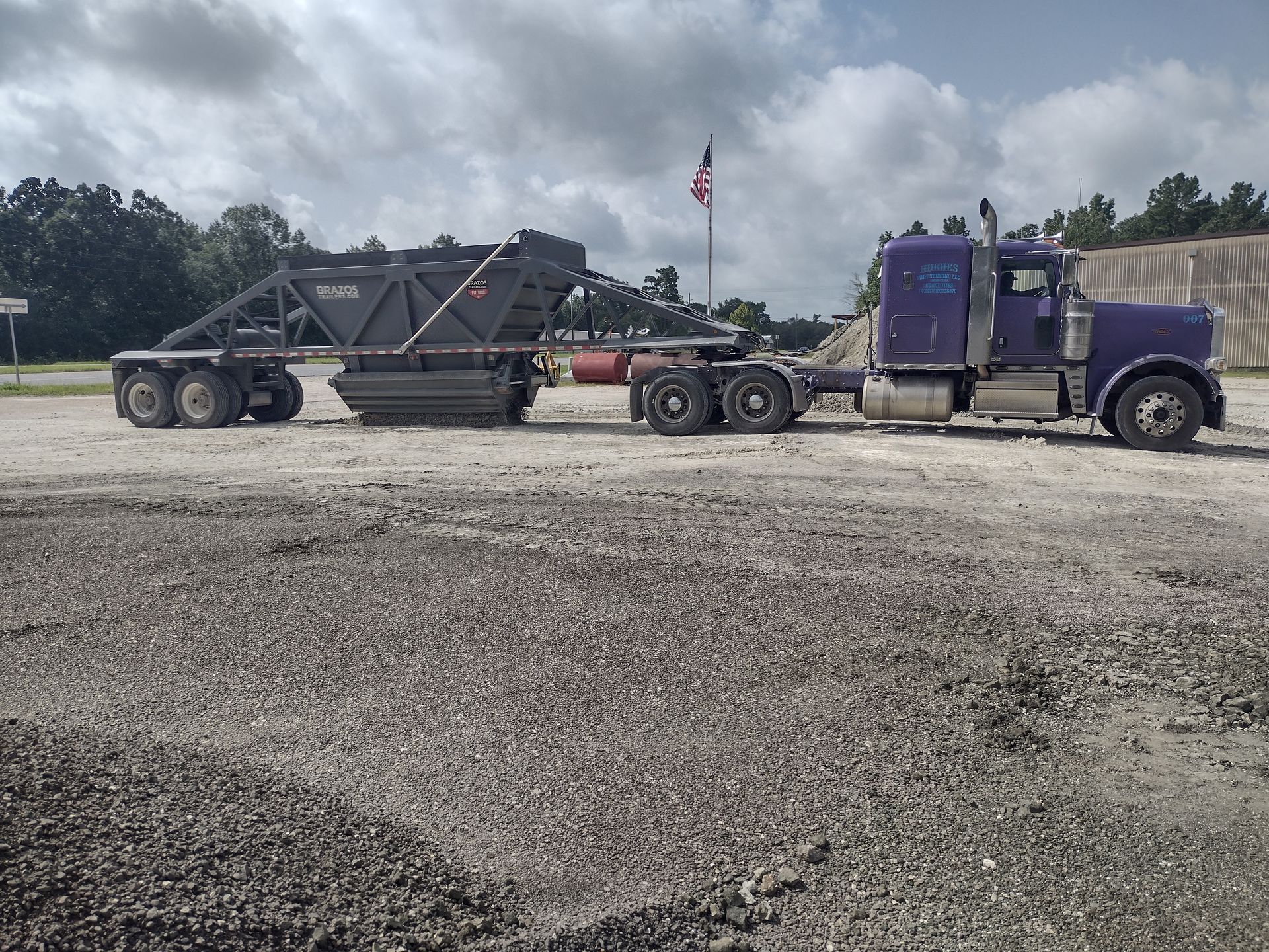 A purple semi truck with a trailer attached to it