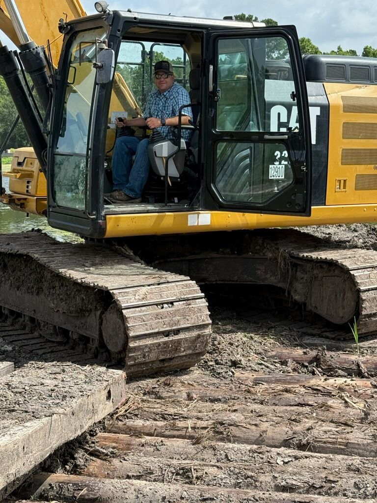 A man is sitting in the cab of a bulldozer.