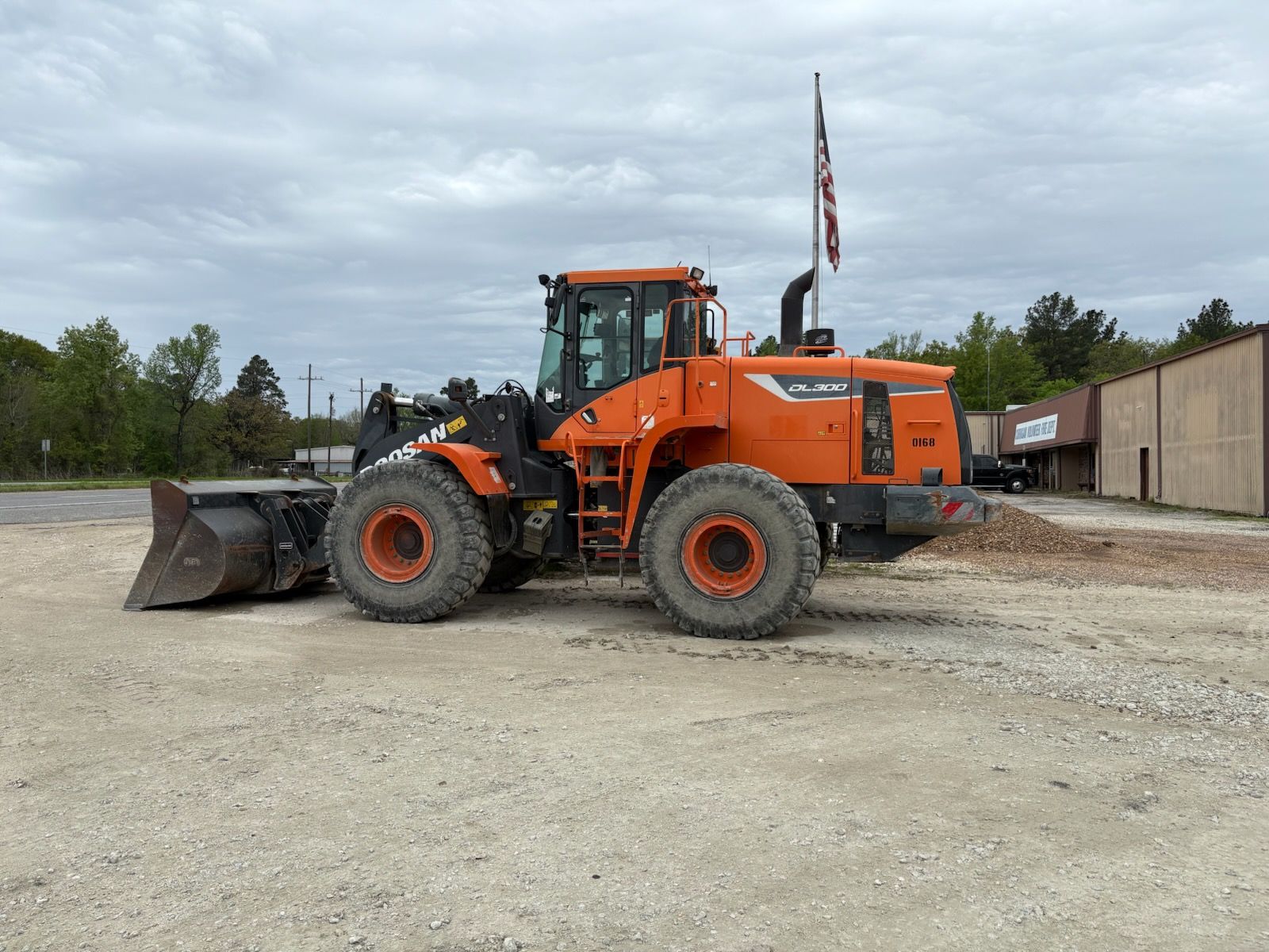 An orange and black wheel loader is parked in a dirt lot.