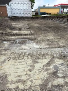 A dirt field with a building in the background and a gas station in the background.