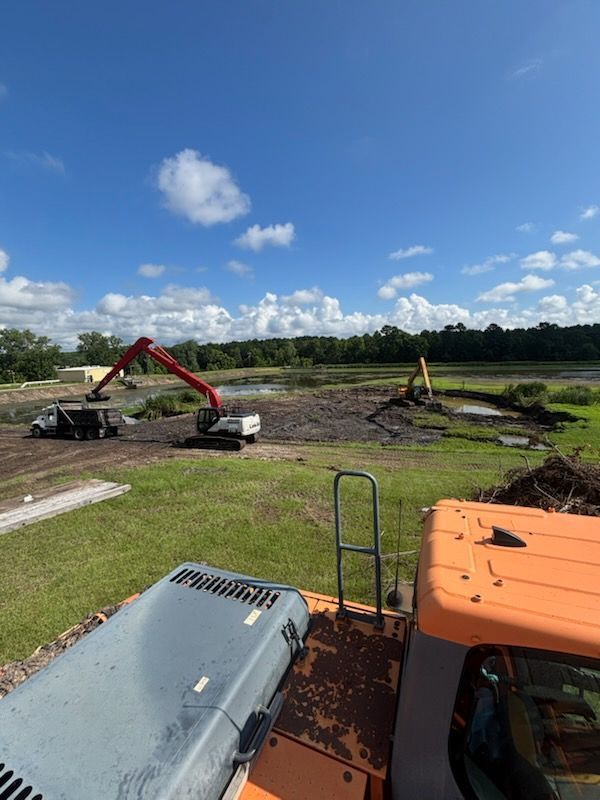 A large orange excavator is working on a construction site.