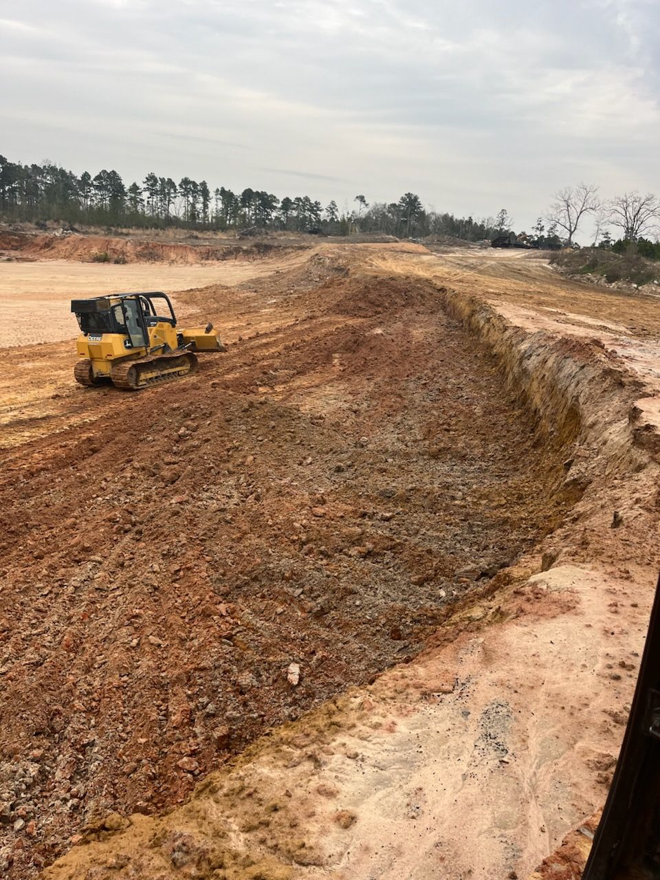 A bulldozer is moving dirt on a dirt road.