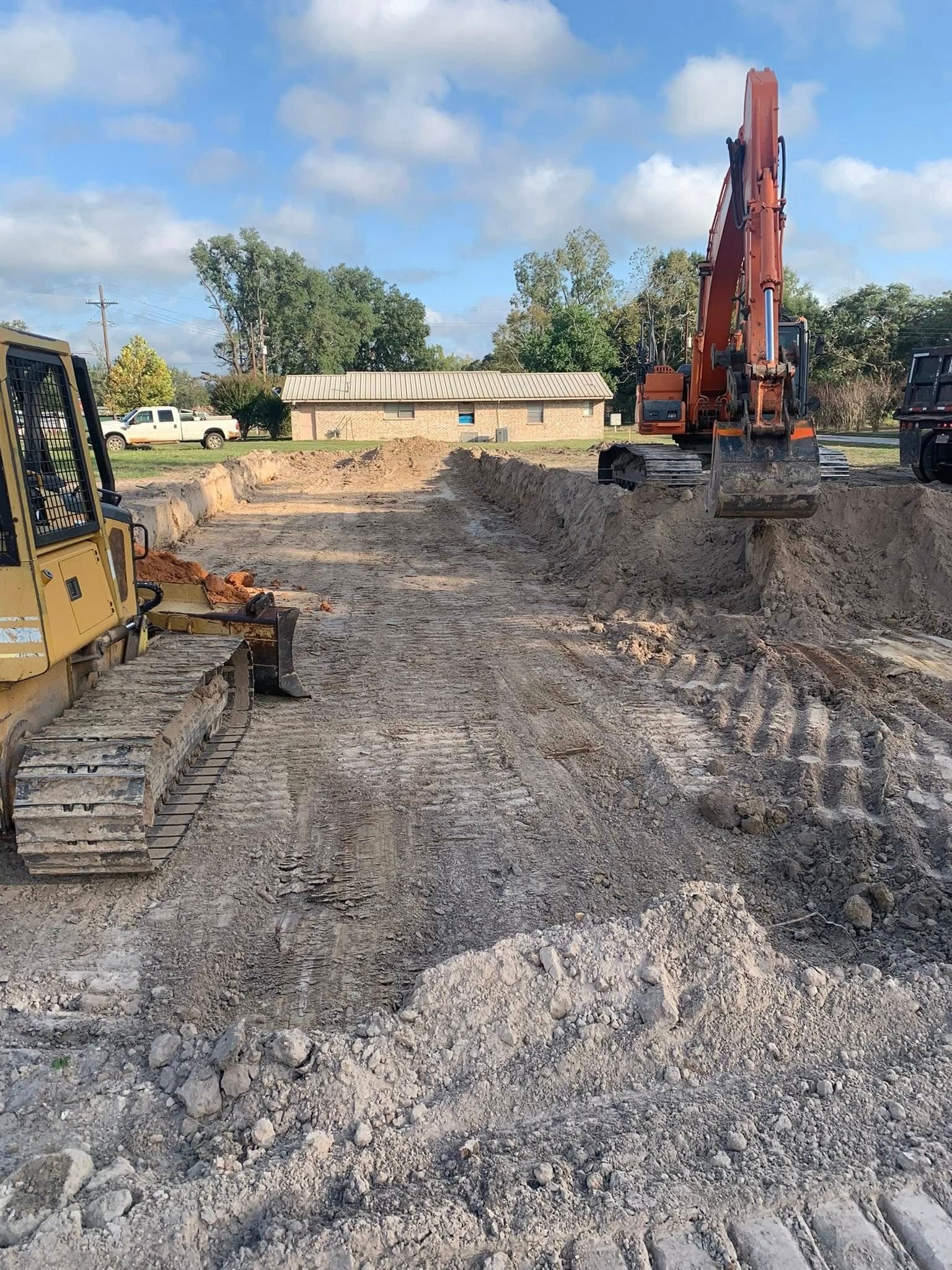 A bulldozer and an excavator are sitting in a dirt field.